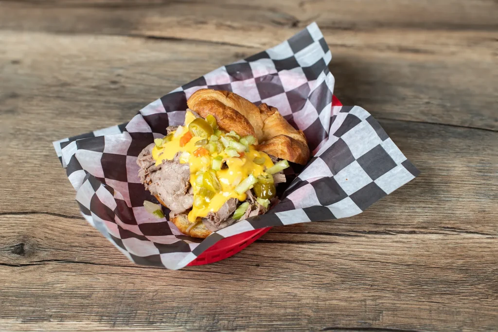 Staleys Italian Cheese Croissant with a checkered wrapper placed on a wooden table.
