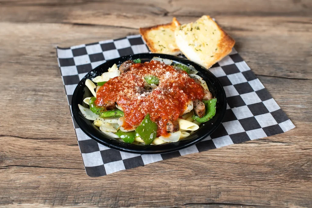 Staleys Pasta Marinara with bread with a checkered wrapper placed on a wooden table.