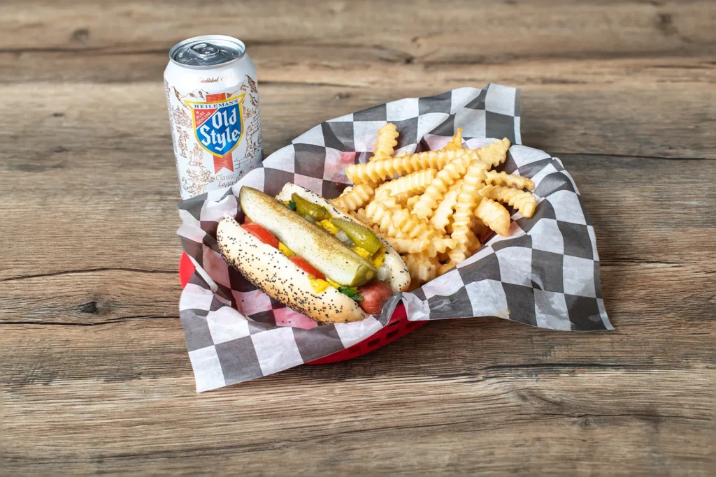 Staleys Old Style, Chicago Hotdog, and crinkle cut fries combo with a checkered wrapper placed on a wooden table.