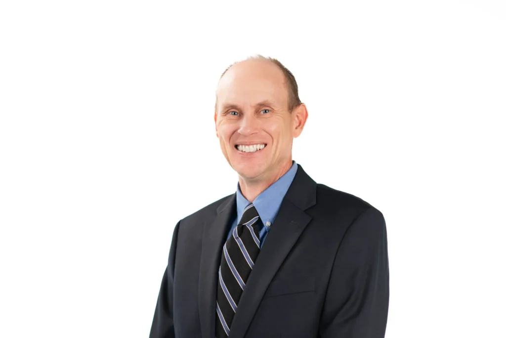 Professional headshot of a man against a white background